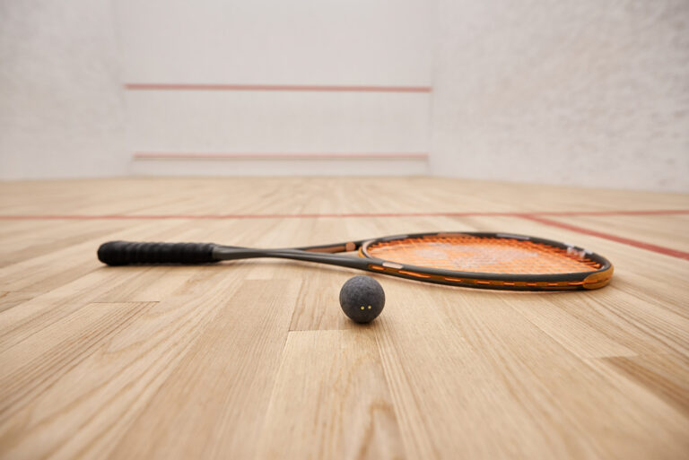ball and racquet on floor inside of indoor squash court, motivat