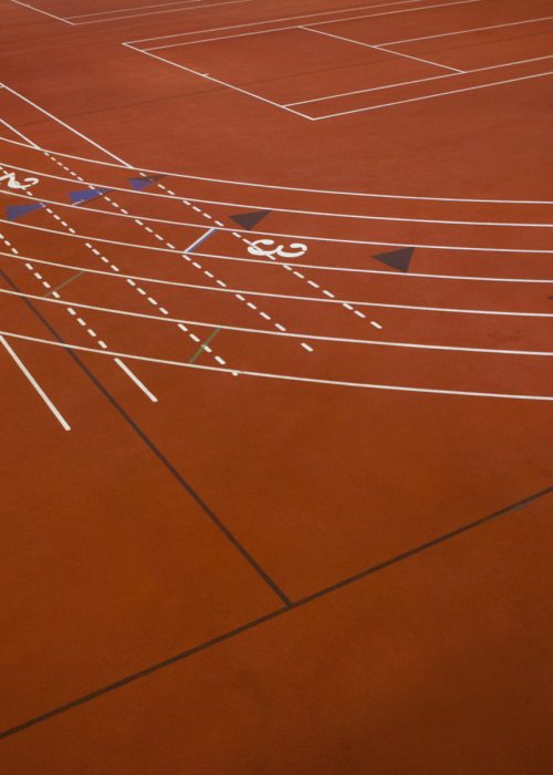 A red running track, athletics ground, a corner section of track marked with lanes