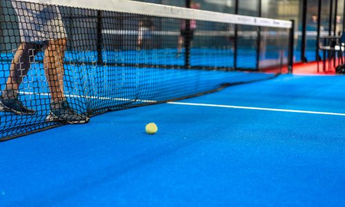 Cropped photo of a tennis ball next to the net while friends playing indoors