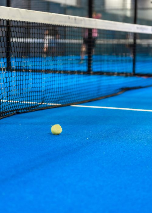 Cropped photo of a tennis ball next to the net while friends playing indoors