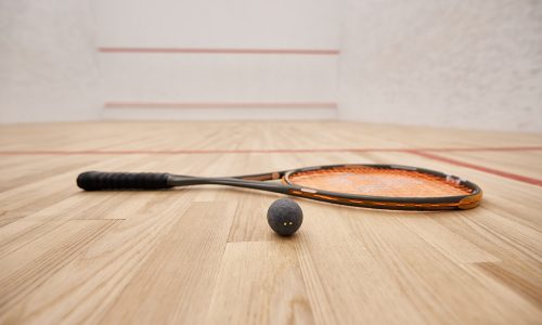 ball and racquet on floor inside of indoor squash court, motivation and determination concept