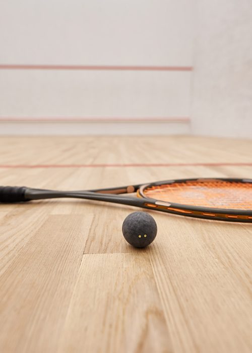 ball and racquet on floor inside of indoor squash court, motivation and determination concept
